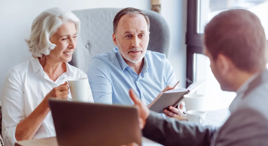 Conseiller funéraire présentant un contrat de prévoyance à un couple de séniors.
